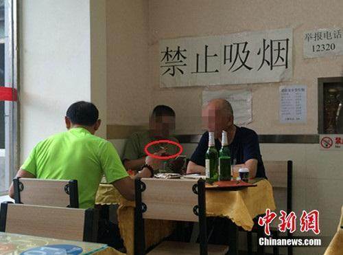 资料图：北京某餐馆，一男子在“禁止吸烟”的标识下抽烟。中新网 邱宇 摄